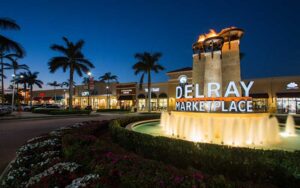 shopping center at night with lighted fountain sign and shops at delray marketplace palm beaches