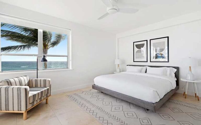 spacious bedroom with king size bed and ocean view window at the ambassador palm beach hotel residences