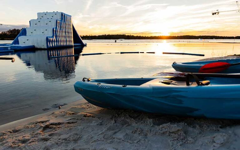 sunset over lake with kayaks and inflatable bouncer at nona adventure park orlando