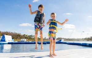 two kids bouncing on aqua park inflatable at nona adventure park orlando