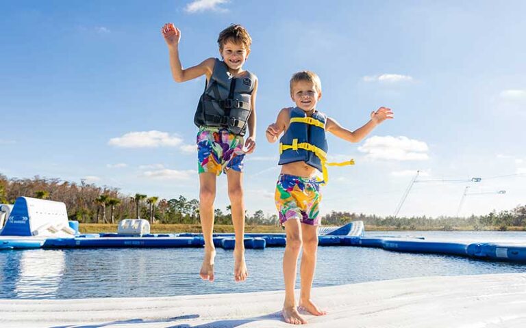 two kids bouncing on aqua park inflatable at nona adventure park orlando