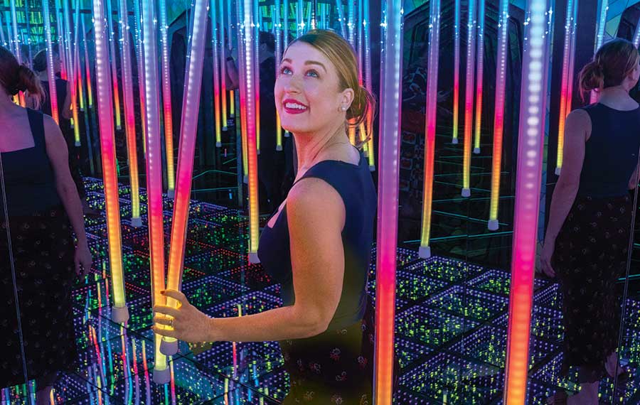 woman wandering through maze of rainbow led light tubes at ripleys mirror maze orlando
