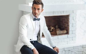 young man wearing white jacket tuxedo with blue pants and bowtie at tux shop palm beach