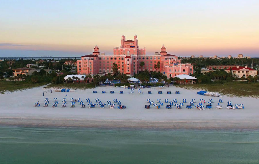aerial view from ocean of pink resort with rows of blue and white striped umbrella loungers on beach at the don cesar st pete beach