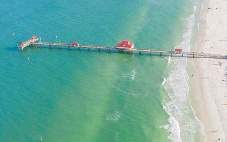 aerial view of beach with green water and long pier at clearwater beach