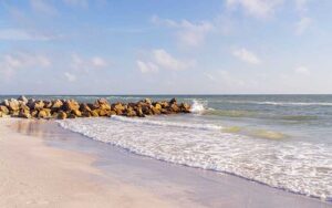 beach with jetty of rocks and flat white sand at sunset beach treasure island st pete