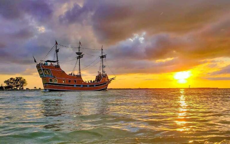 beach with red galleon ship and cloudy sunset at captain memos pirate cruise clearwater