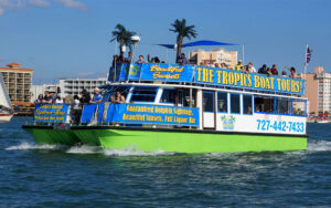 catamaran style tour boat moving through inlet with sailboat and hotels in background at the tropics boat tours clearwater beach