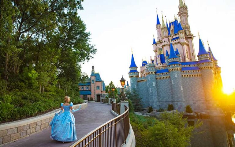 cinderella costumed character walking up ramp toward cinderella castle with sun peaking at magic kingdom walt disney world resort orlando