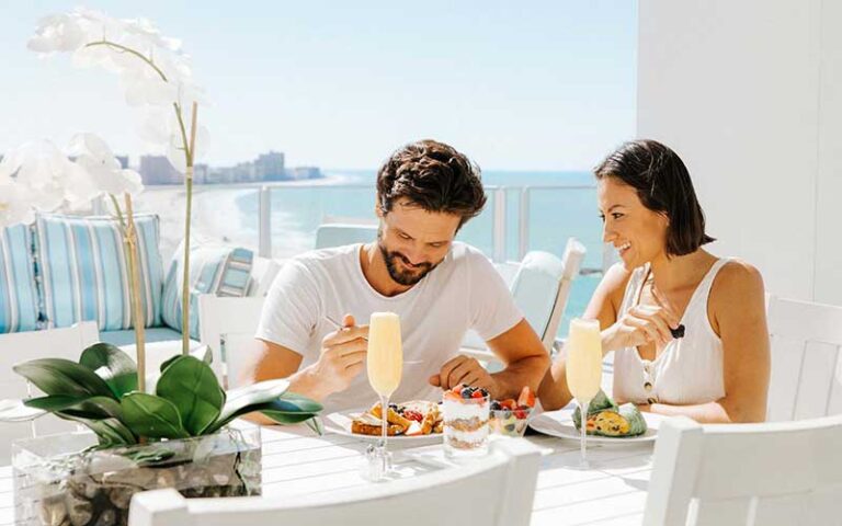 couple enjoying breakfast on patio with shoreline in background at opal sands resort clearwater beach