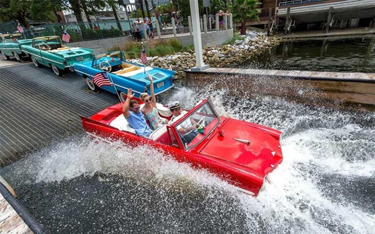 couple riding with captain in red vintage car style boat launch at the boathouse at disney springs orlando