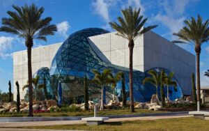 daytime exterior of museum with glass globe extension atria and palm trees at salvador dali museum st pete