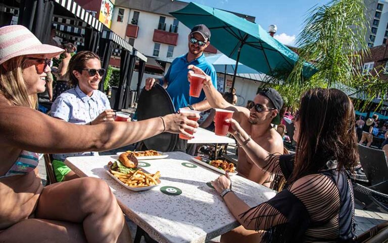 diners toasting drinks at patio table at hollander hotel st pete