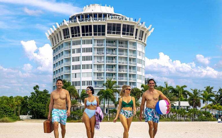 group of beachgoers walking with hotel in background at bellwether beach resort st pete beach