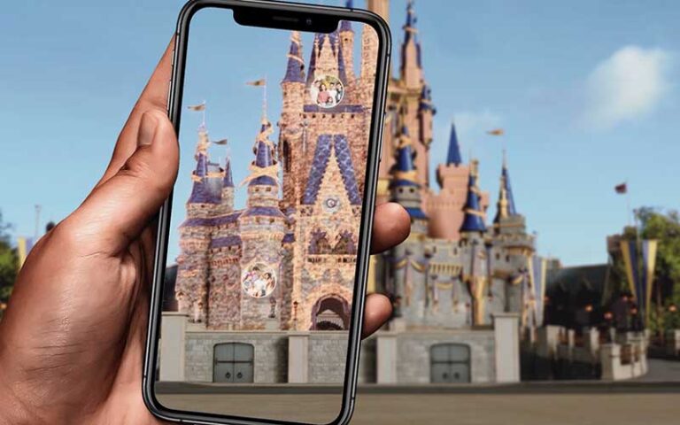 hand holding up smartphone with ar shown on screen with family photos mural at magic kingdom walt disney world resort orlando