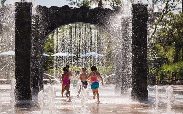 kids playing in splash pad with waterfall archways at four seasons resort orlando walt disney world