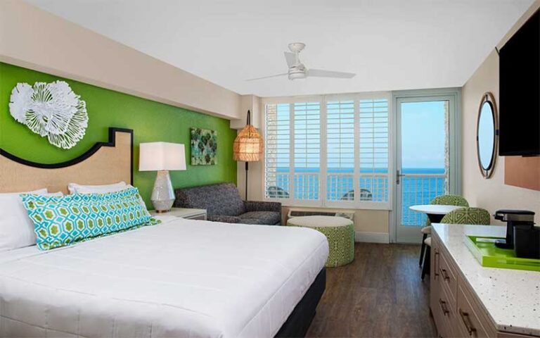 king bed guestroom with green accents and ocean view at bellwether beach resort st pete beach