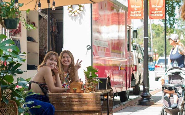 ladies at table on sidewalk with clothing racks on truck at safety harbors market on main clearwater