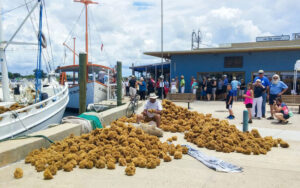 man with piles of sponges on dock next to boats at tarpon springs sponge docks