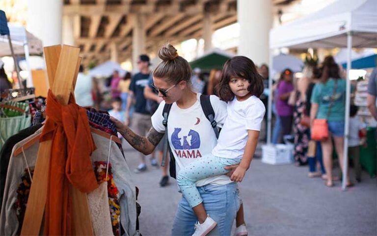 mom holding toddler while shopping at st pete indie flea