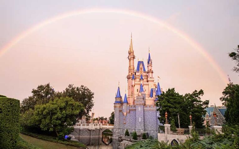 rainbow arching over cinderella castle with pink sky at magic kingdom walt disney world resort orlando