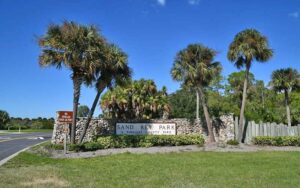 roadside sign and trees with clear blue sky at sand key park clearwater