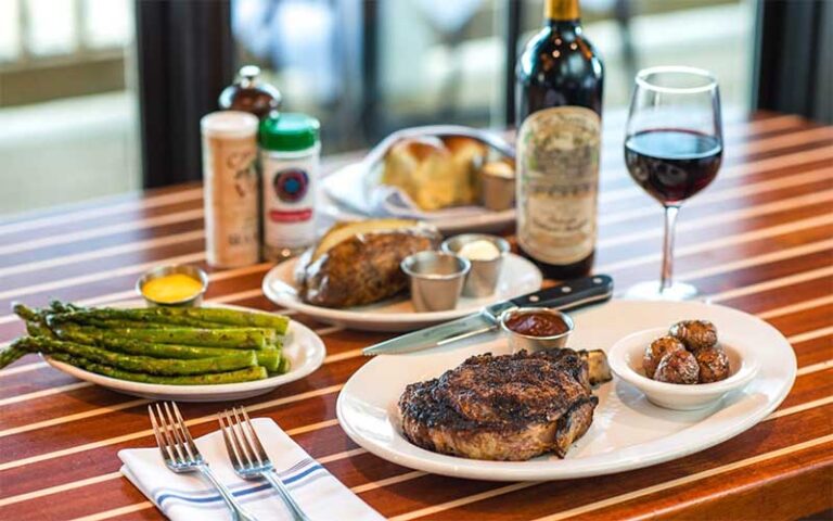 steak entree with sides and wine on tabletop at the boathouse at disney springs orlando