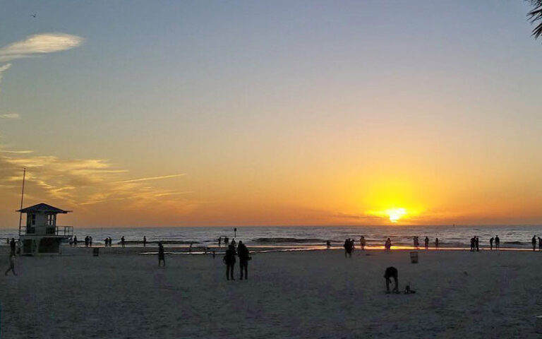 sunset over beach with couple and lifeguard shack at pier 60 park clearwater beach