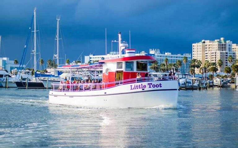 tugboat in harbor with ships and hotel in background at little toot dolphin adventure clearwater beach