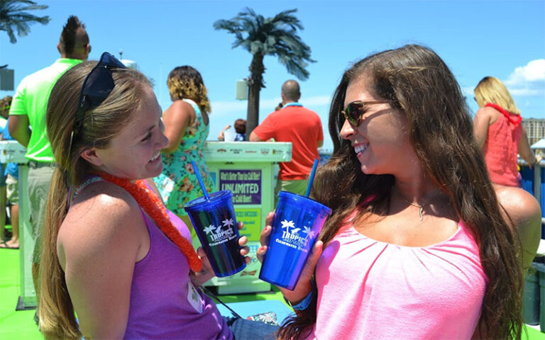 two ladies drinking from branded cups on boat dock at the tropics boat tours clearwater beach