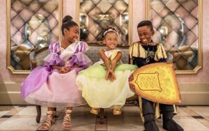 two young princesses and a knight seated on bench with mirrors at bibbidi bobbidi boutique at magic kingdom walt disney world resort orlando