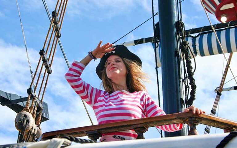 woman in pirate costume at ships helm looking out at captain memos pirate cruise clearwater