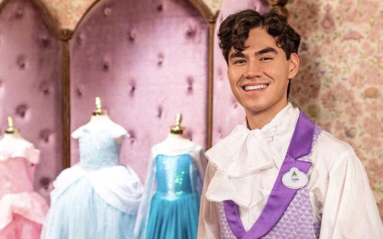 young man in prince costume with dresses on manekins at bibbidi bobbidi boutique at magic kingdom walt disney world resort orlando