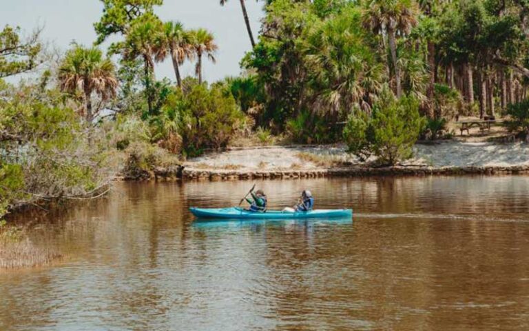 couple kayaking along river with trees at tomoka state park ormond daytona beach