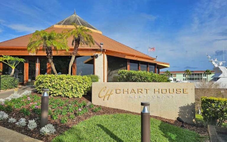 daytime exterior of restaurant with sign and marina at chart house daytona beach