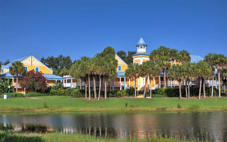 yellow and white hotel buildings viewed across lake at caribbean beach resort walt disney world orlando