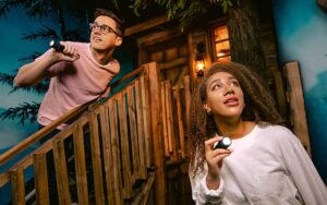 couple searching room with flashlights at the escape game
