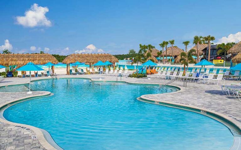 curvy pool area with loungers and tiki huts at camp margaritaville auburndale