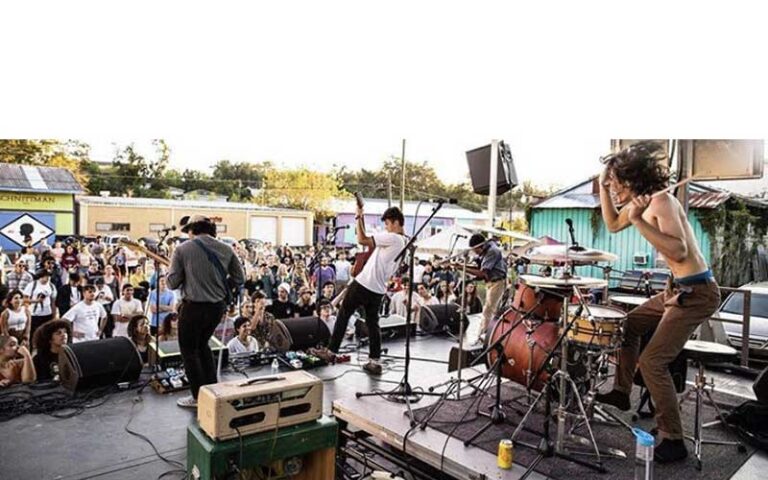 rock band performing on outdoor stage with crowd at rainbow square art district tallahassee