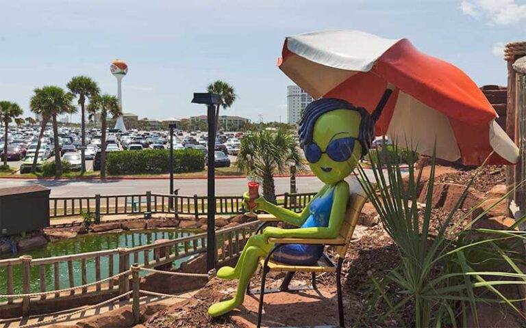 alien sunbather figure on golf course with watertower in background at ufo golf pensacola beach