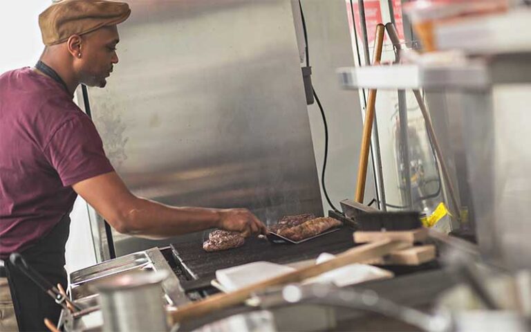 cook in kitchen grilling meat at table 23 tallahassee