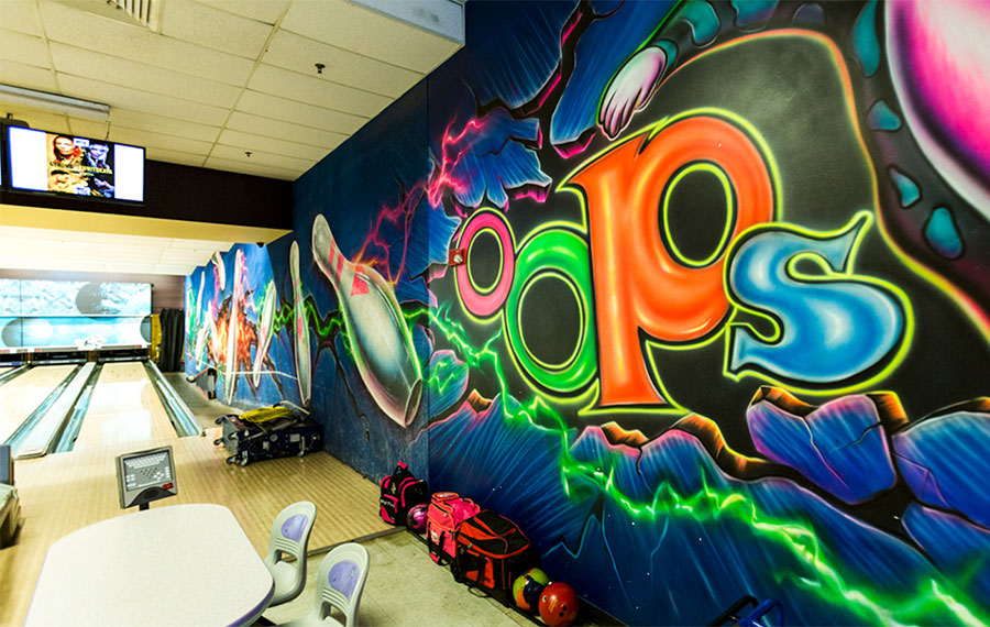 bowling lanes with colorful mural of giant pins at oops alley family entertainment center pensacola