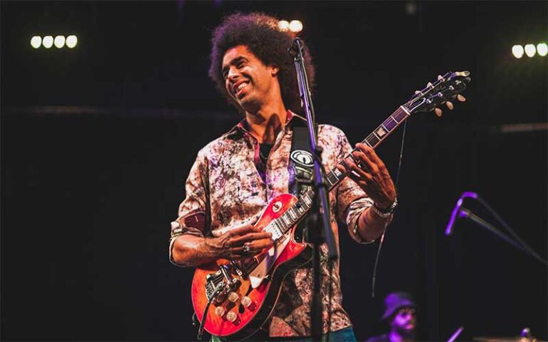 smiling performer with electric guitar and mic at arts garage delray beach