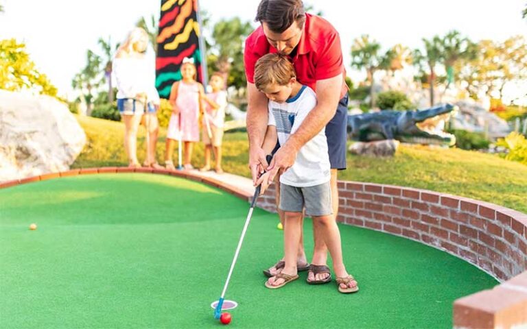 dad helping kid putt at coconut creek family fun park panama city beach