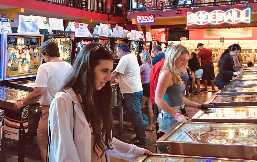 girl playing pinball machines with arcade background at silverball retro arcade delray beach