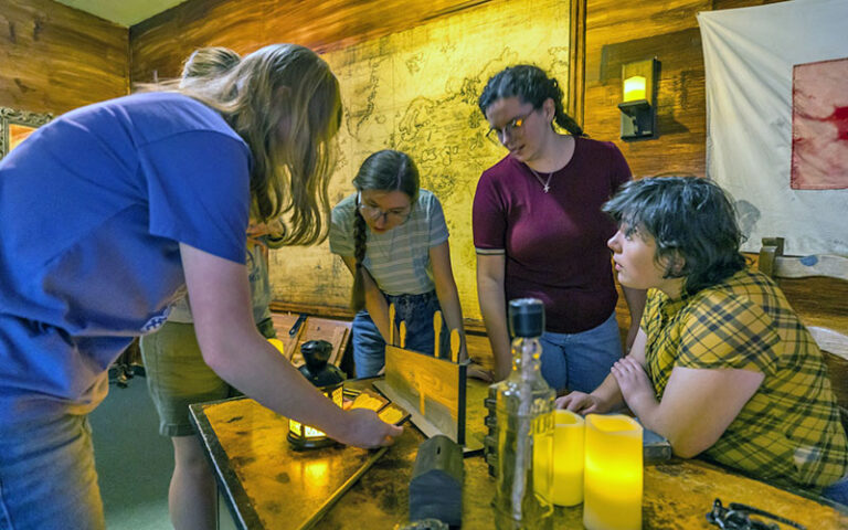 group of people around desk looking through items at amelia island escape rooms