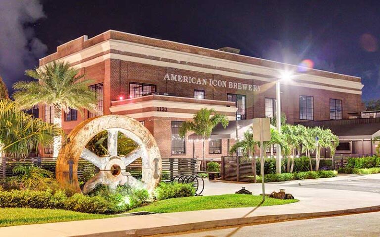 night exterior of building with giant gear statue at american icon brewery vero beach