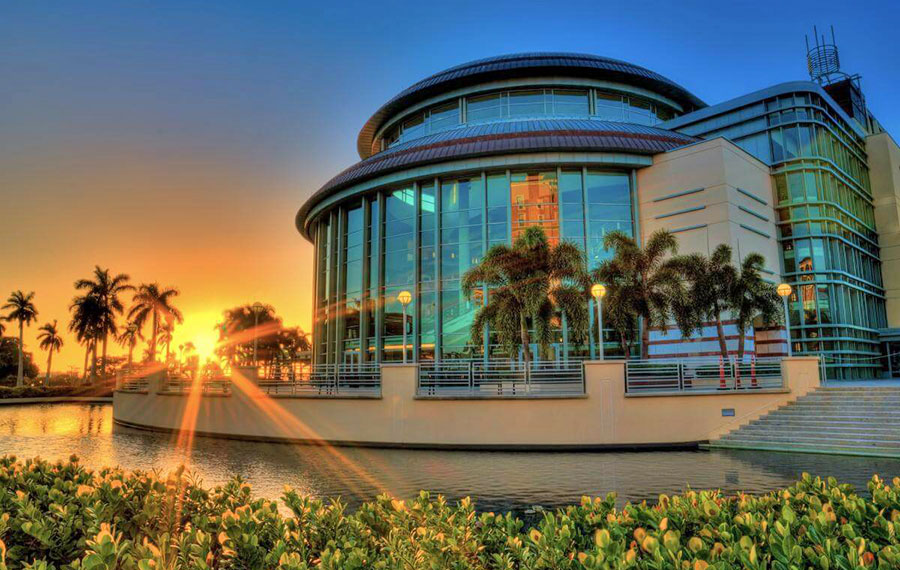 sunset peaking through trees beside kravis center west palm beach
