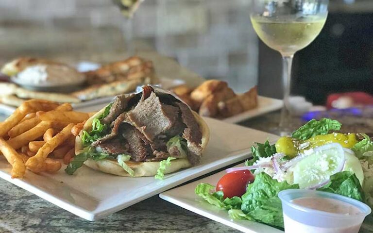 table with entrees of greek food and wine at spiros taverna of st lucie west