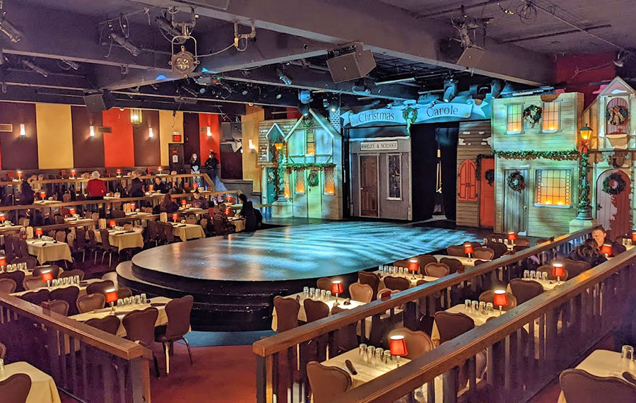 tiered dining area with tables surrounding a stage with set and low lighting at alhambra theatre jacksonville